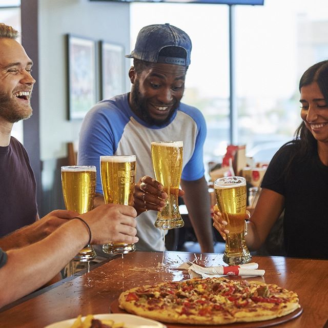 Four friends toasting drinks at Boston's.