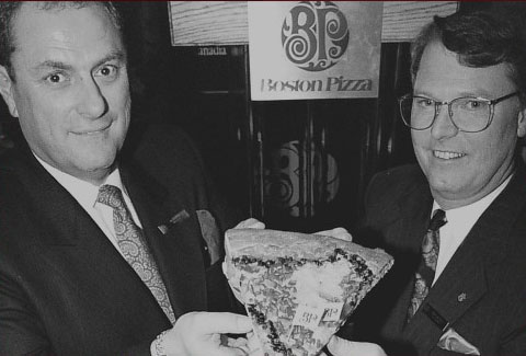 Jim Treliving and George Melville sharing a slice of pizza