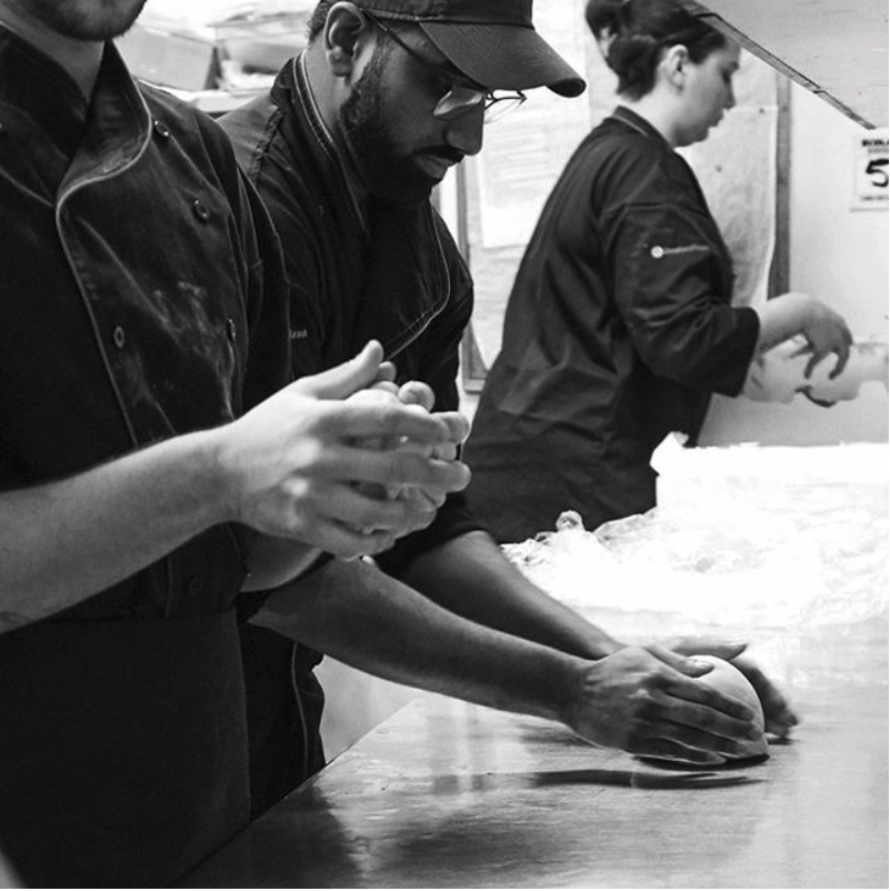 Photp pf three people in the kitchen rolling dough.