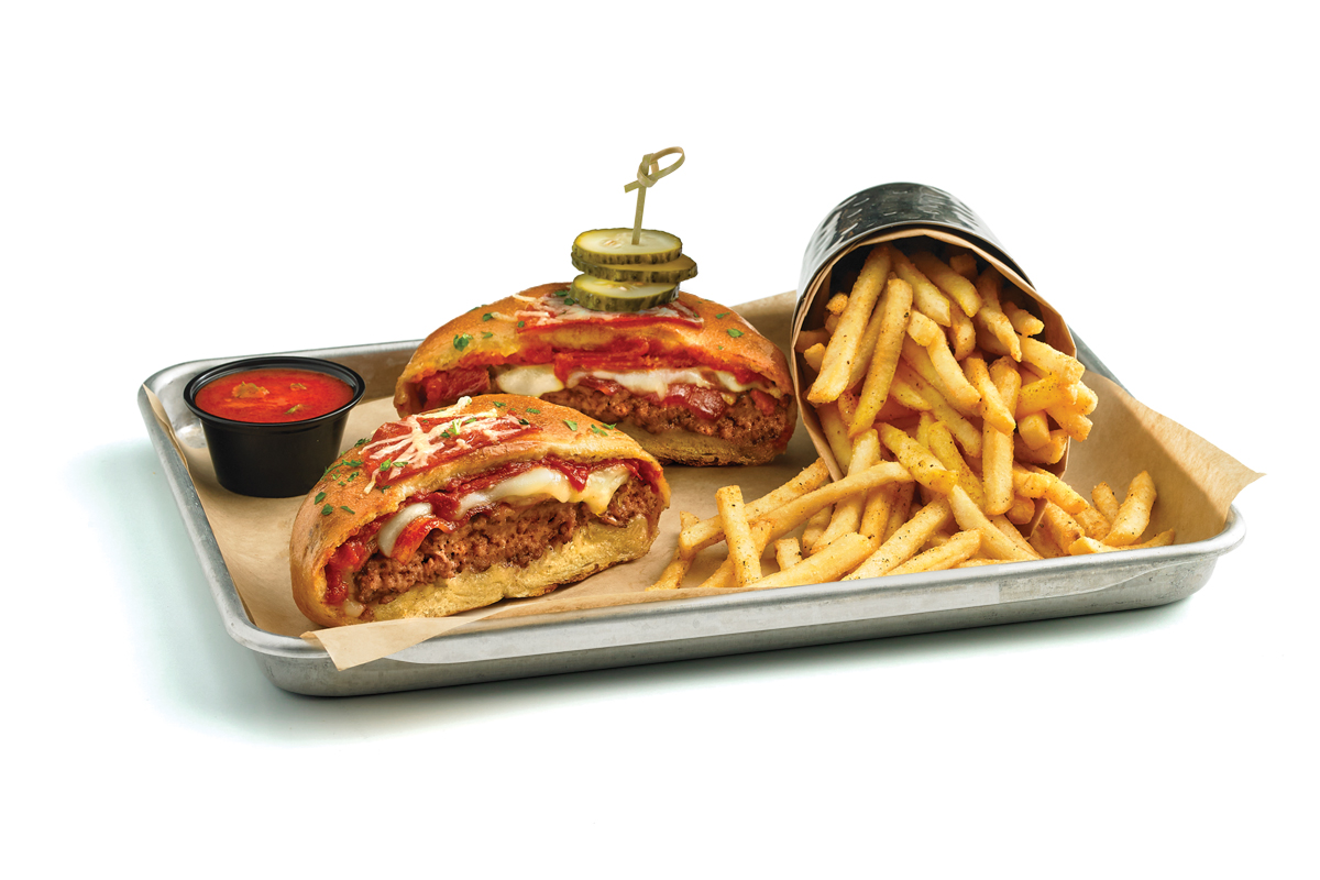 photo of pizzaburger with pickles on top and a side of fries