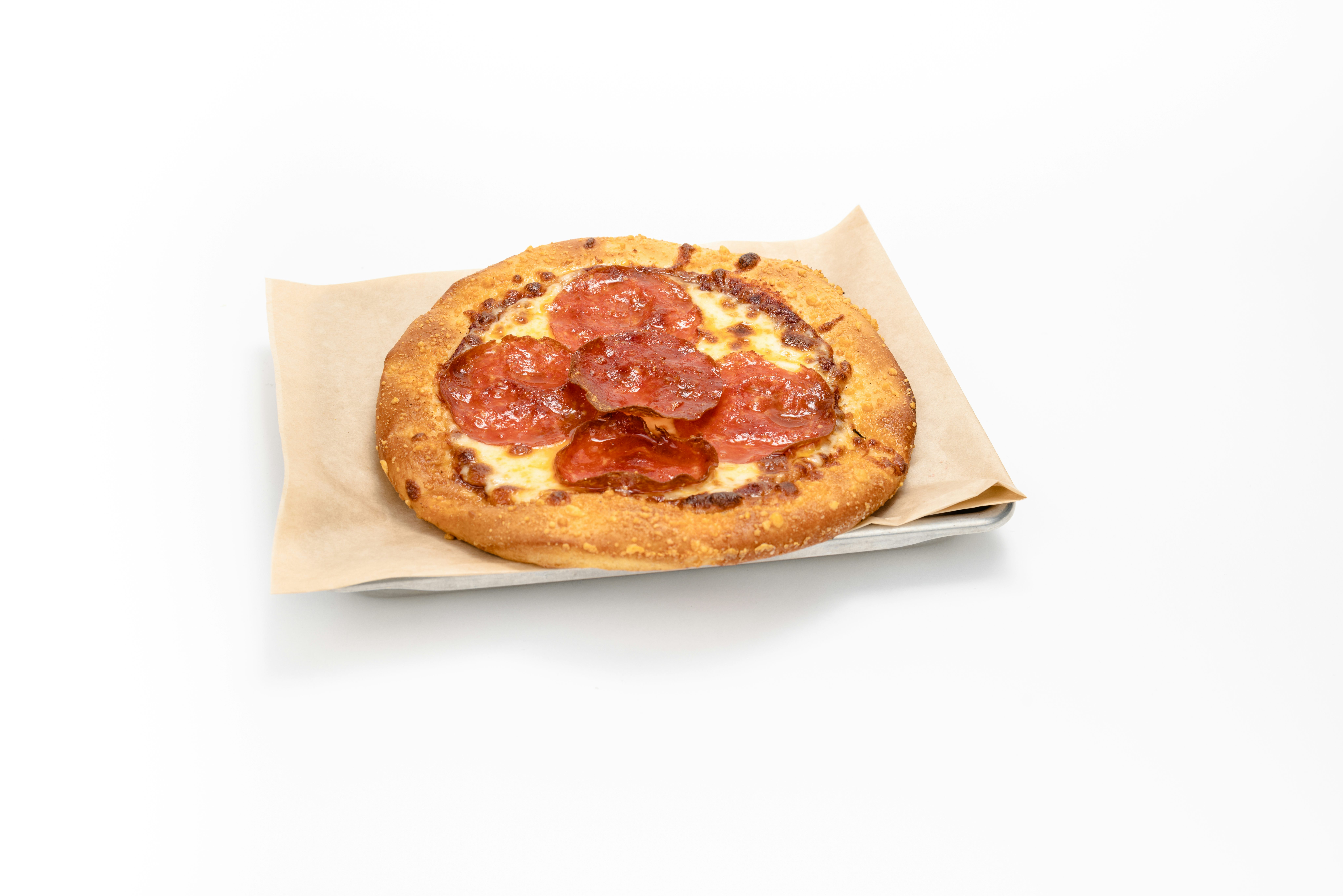 Image of kid's pepperoni pizza on a sheet pan and brown parchment paper. 