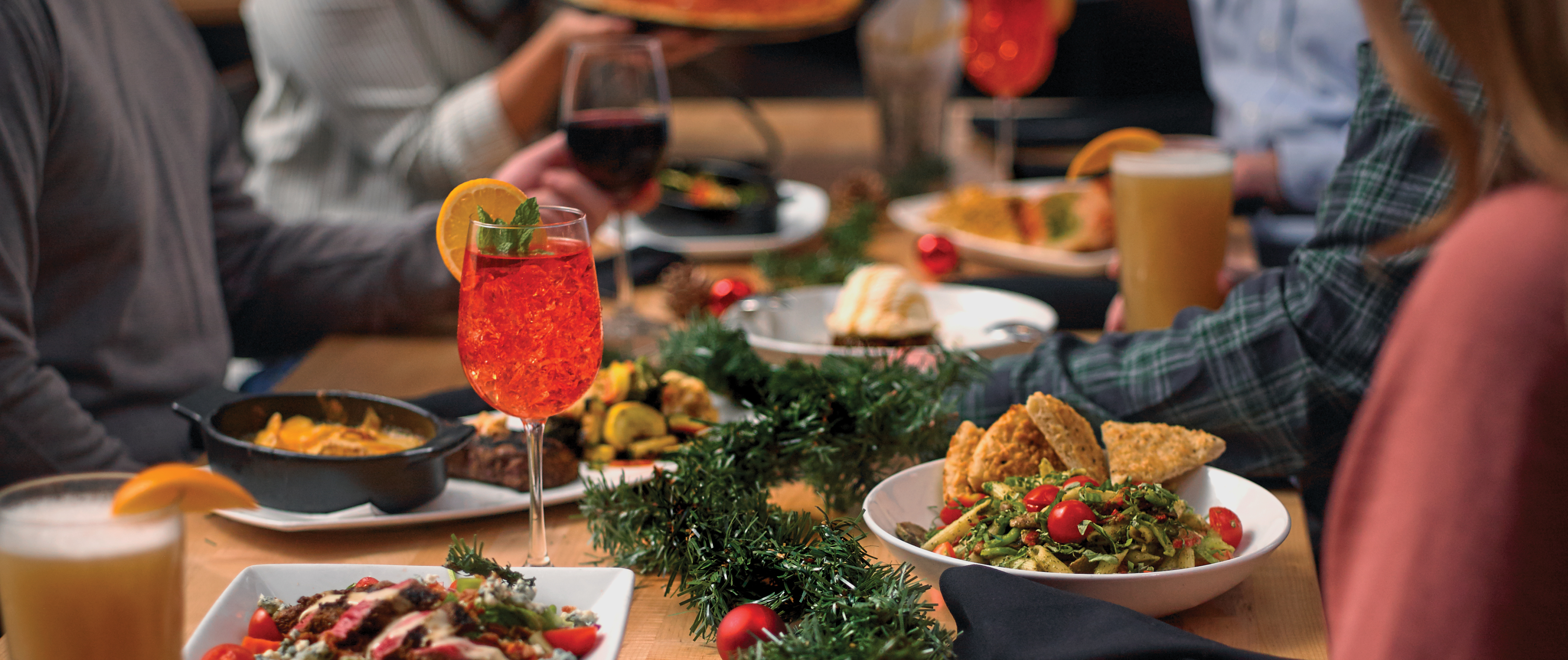 Assortment of holiday favorites on a wood table with a group gathered around. 