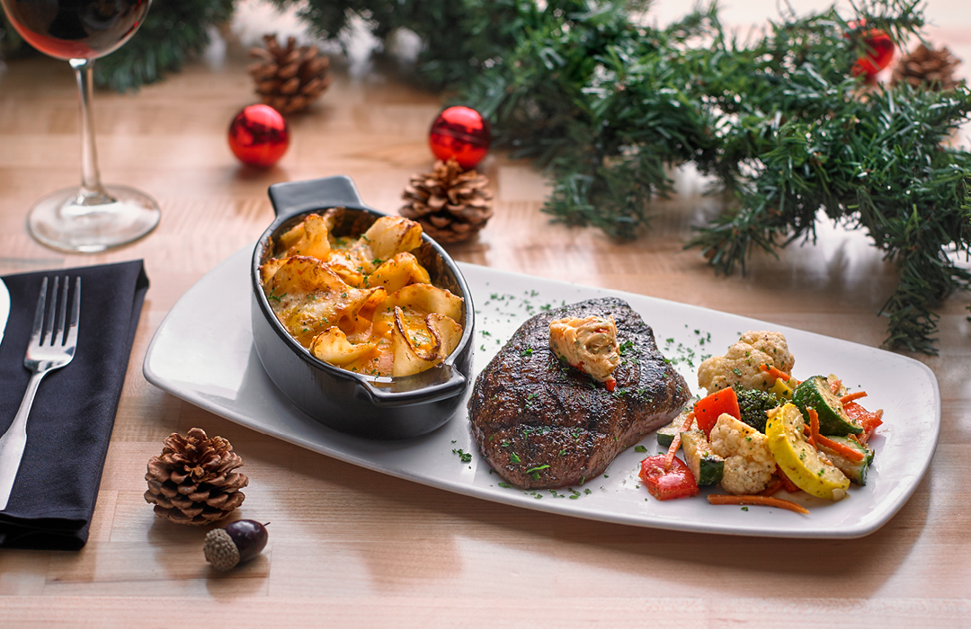 Grilled steak, roasted vegetables, and potatoes, served on a white plate