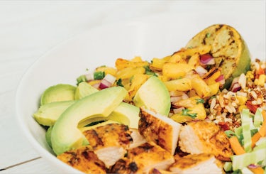 image of diced chicken, rice quinoa blend, sliced avocado, and pineapple salsa in a bowl.