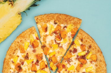 overhead image of tropical chicken pizza with one slice being pulled out.