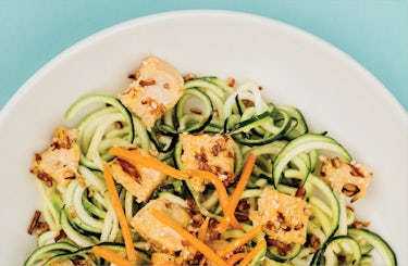 Image of zucchini noodles, diced chicken, shredded carrots, and sesame seeds in a bowl.