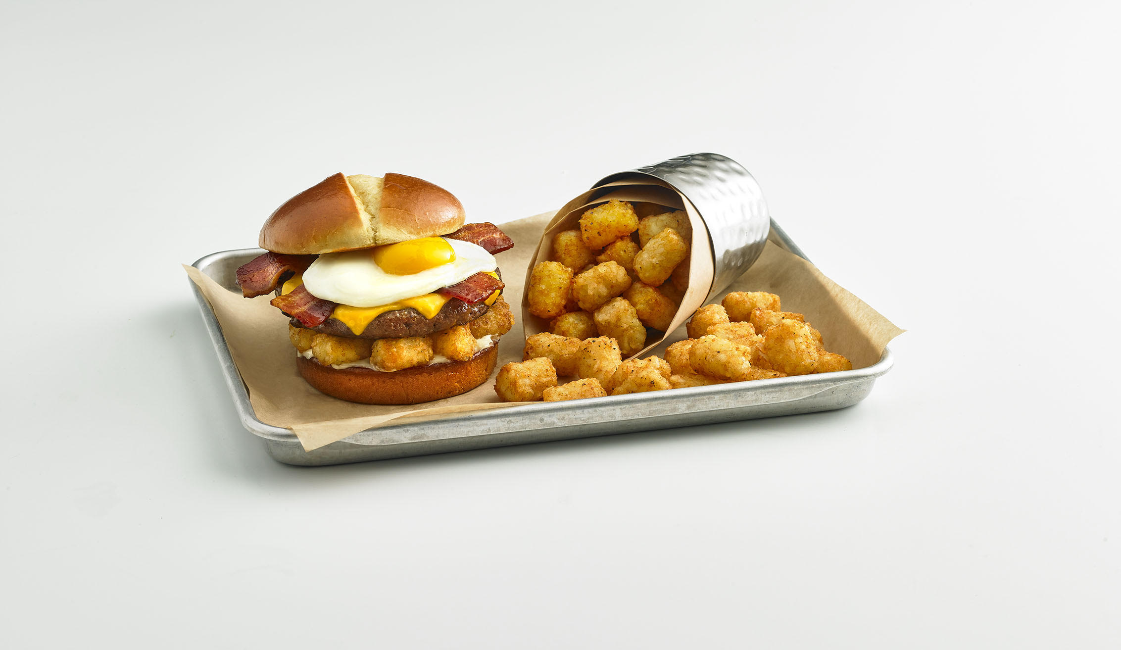 Burger with a Sunnyside up egg and tater tots.