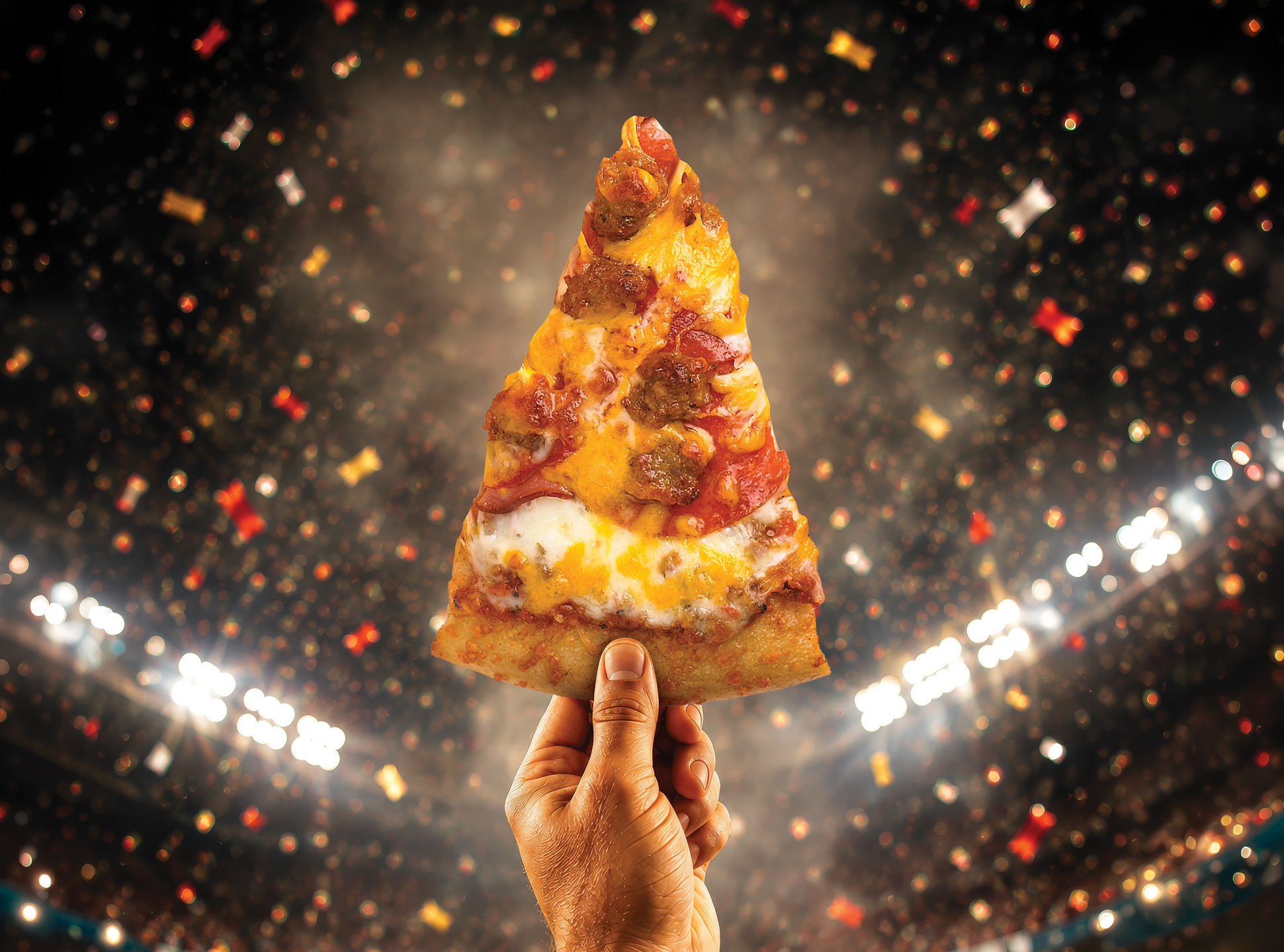 image of hand holding a pizza in a stadium with celebrations in the background